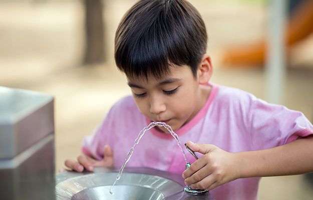 A young boy drinking from a water fountain.