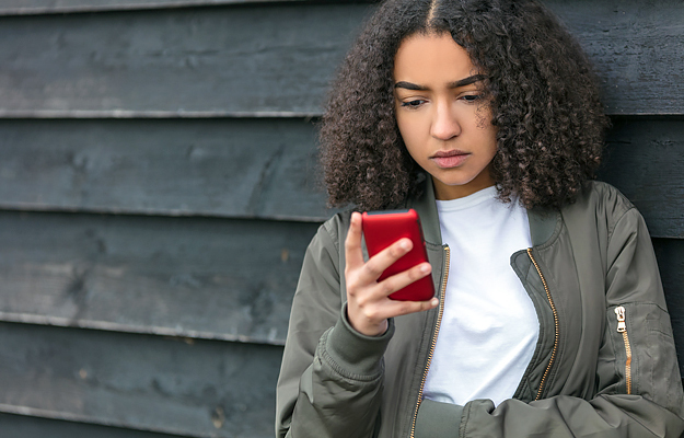 A teenage girl looking down at a cell phone.