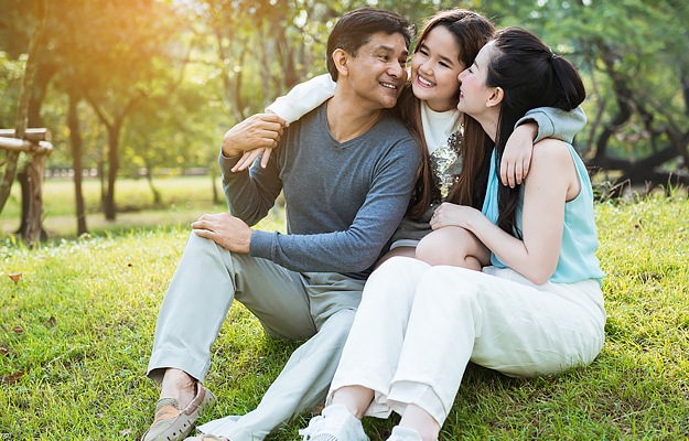 A couple sitting outside with their young daughter.