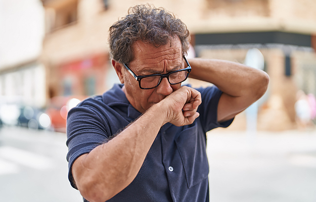 A mature man coughing.