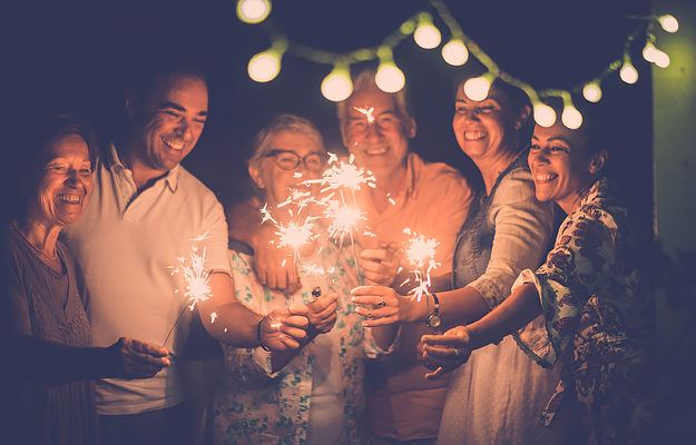 A group of smiling people holding sparklers.