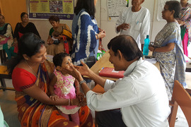 Child sits in mothers lap during an examination in an Indian clinic.