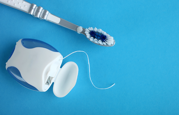 A toothbrush and dental floss on a blue background.