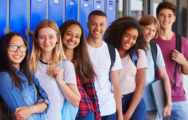 A group of teenagers standing in front school lockers.