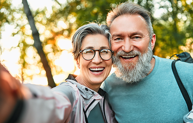 A smiling mature couple taking a selfie outside.