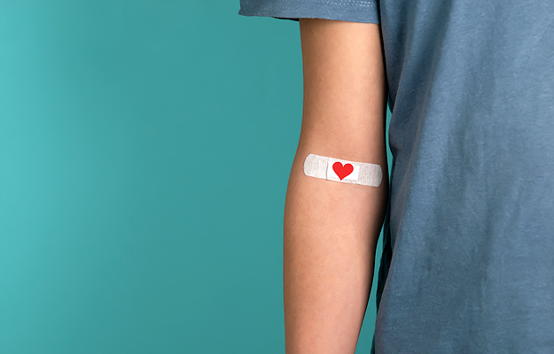 A close-up of an arm with a heart Band-Aid over the inner elbow.