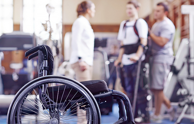 A man receiving physical therapy with a wheelchair in the foreground.