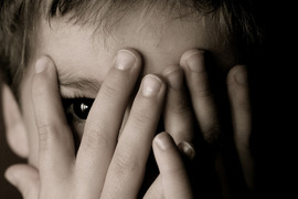 Child hiding face and looking through his fingers.