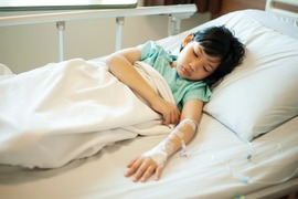 Sick young girl asleep in a hospital bed.