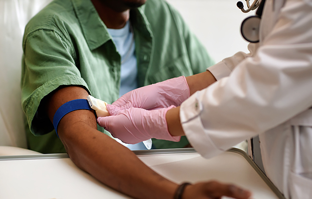 A close-up of a nurse preparing a patient's arm for a blood test.