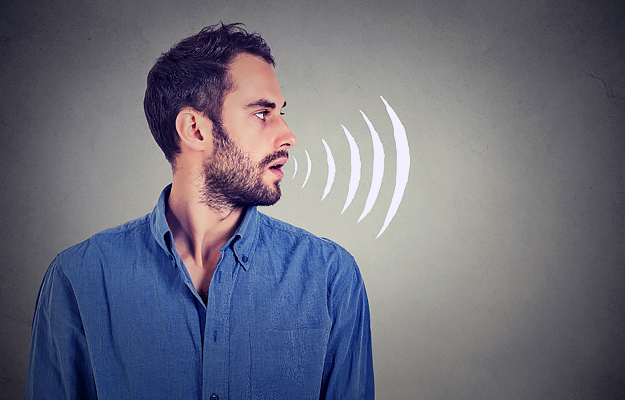 The profile of a man with a sound icon next to his open mouth.