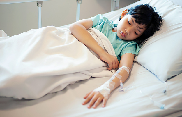 A sick young girl asleep in a hospital bed.