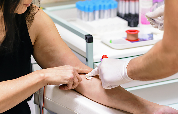 A cotton swab pressed onto a woman's arm after blood collection.