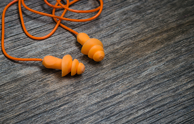 A pair of orange high fidelity earplugs on a wooden background.