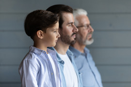 Boy standing in a row with young father behind him and grandfather in back.