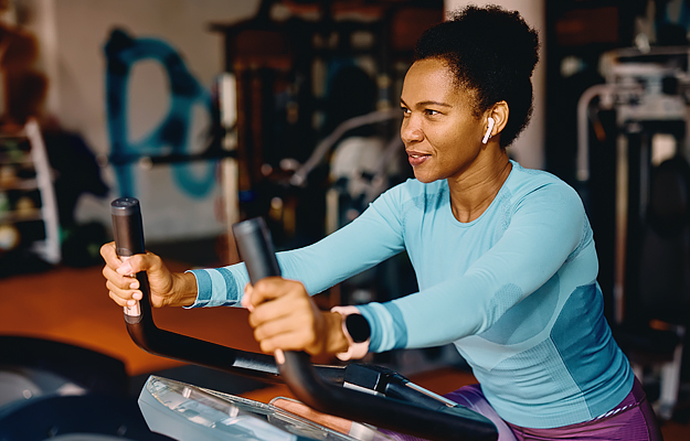 A middle-aged woman riding a stationary indoor-cycling bike.