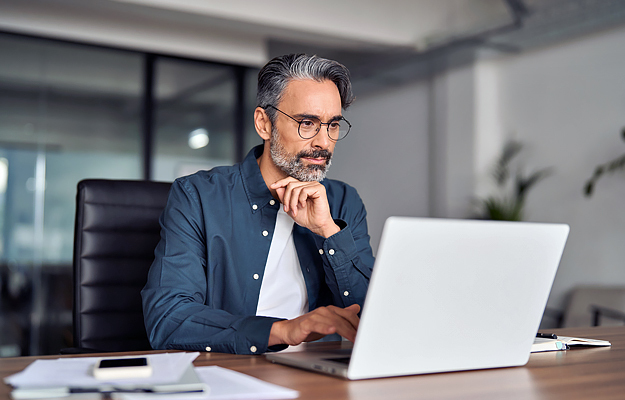 A man sitting at a desk and using a laptop.