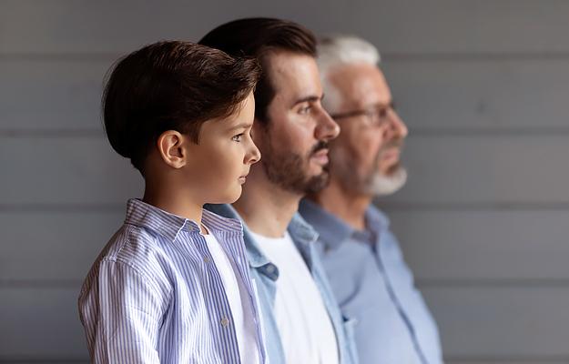 A young boy standing in a row with his father and grandfather.