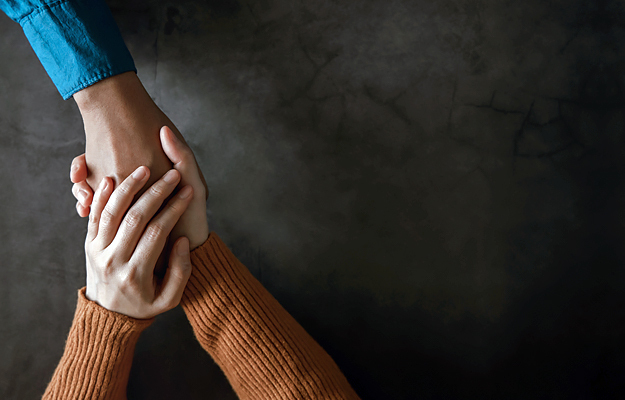 A close-up of someone holding another person's hand in theirs.