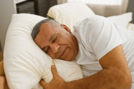 Mature Latino man sleeping peacefully in bed.