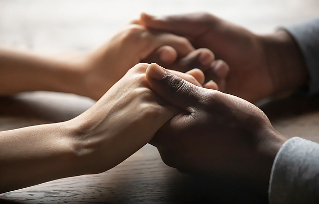 A close-up of a man's hands holding a woman's hands.