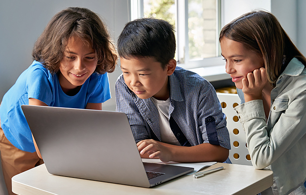 Three kids looking at a laptop.