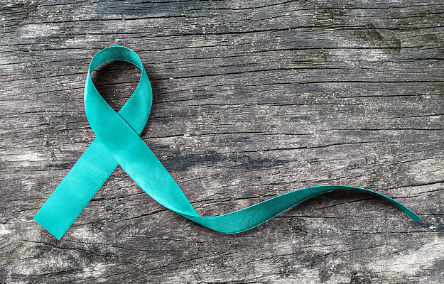 A teal awareness ribbon on a wood surface.