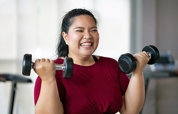 A smiling woman working out with dumbbells.