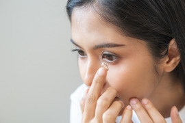 Teen putting a contact in her eye.