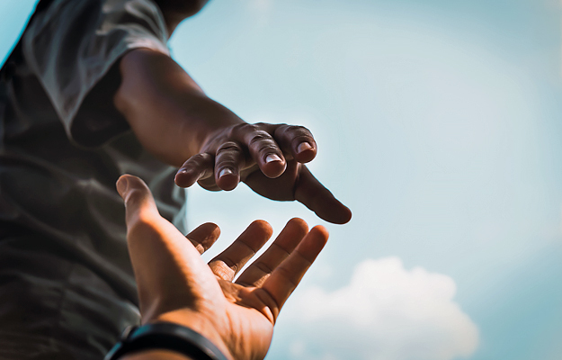 A close-up of a man reaching for someone's hand.