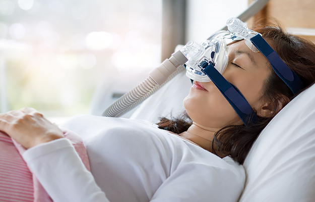 A woman sleeping with a continuous positive airway pressure (CPAP) mask on.