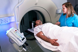 Technician preparing man for a CT scan.