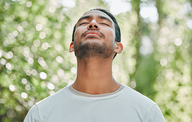 A man with his eyes closed practicing mindfulness outside.