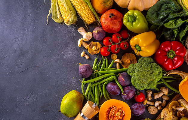 An array of fruits and vegetables on a dark surface.