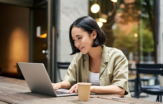 A young woman looking at a laptop at a cafe.