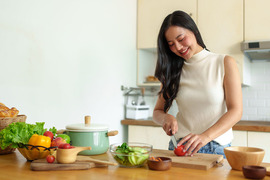 Woman cutting a tomato to make a salad in the kitchen.