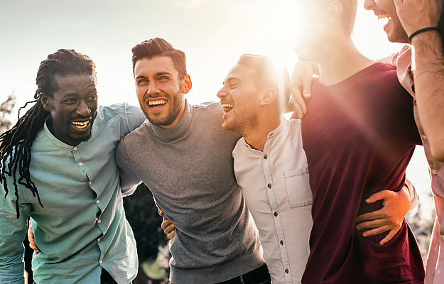 A group of diverse young men huddling together outside.