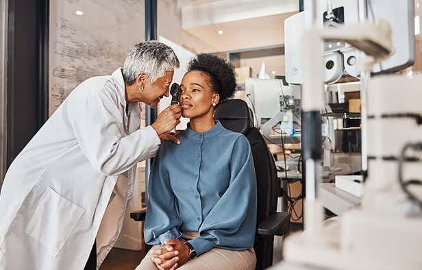 An optometrist performing an eye exam on a female patient.