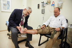 A doctor examines a man’s ankle.