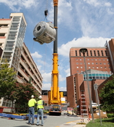 The crane lifts the magnet in the air as two men look up.