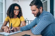 Shot of two business persons filling in paperwork in an office. 