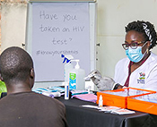 Dr. Patience A. Muwanguzi pointing to test results meets with a patient in a clinic