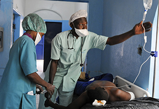 Nadife and Mahamat Saleh administer an IV solution to a patient prior to surgery April 15.