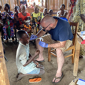 Dr. Matthew Bramble takes a sample from the mouth of a child affected by konzo in Kahemba