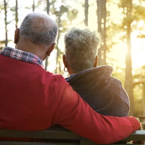 Active, mixed race senior adult couple enjoy outdoor park in spring or autumn season at sunset.