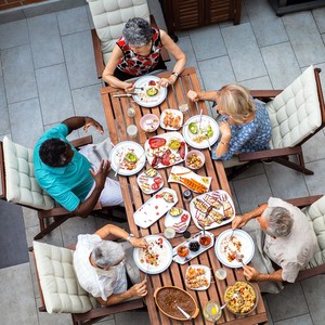 Group of senior friends enjoying in vegan meal in backyard. High angle of view.