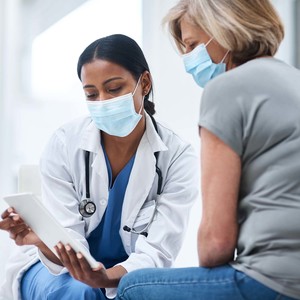 Shot of a young doctor using a digital tablet during a consultation with a senior woman