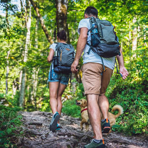 Couple with a small yellow dog hiking in forest