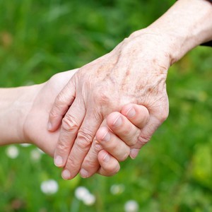 Two seniors holding hands above grass and flowers in a field. 