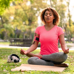 A woman is exercising yoga and meditation in the park. 